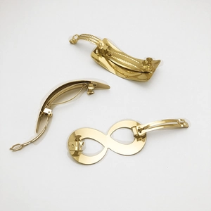 Detailed back view of three gold metal hair clips showing spring clasp mechanism