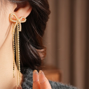 Close-up of elegant bow tassel earrings with sparkling zircons on a model's ear