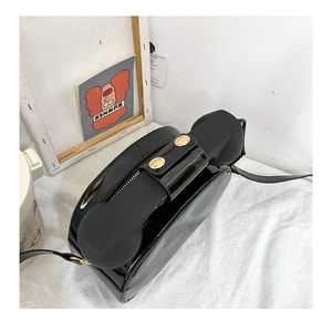 Detail view of glossy black telephone-shaped handle and metal clasp on creative crossbody bag
