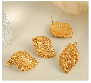 Vue détaillée de boucles d'oreilles dorées rétro avec texture feuille sur fond beige