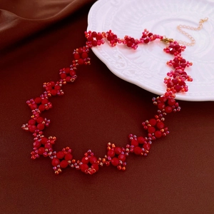 Détail macro du collier de fleurs rouges avec perles dorées sur une assiette en céramique
