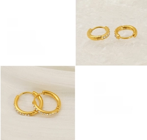 Close-up of gold titanium steel huggie earrings with sparkling cubic zirconia inlay