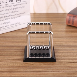 Detail of Newton's cradle with five metal balls on a wooden desk with bokeh background