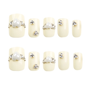 Unghie finte color crema con strass scintillanti e decorazioni di perle bianche a cuore