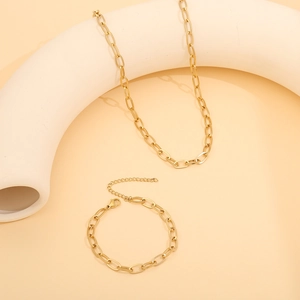 Artistic display of gold-tone heart necklace and bracelet set on stone props