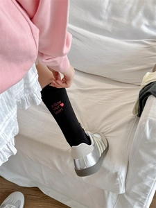 Close-up of black mid-calf socks featuring red Follow your heart embroidered letters