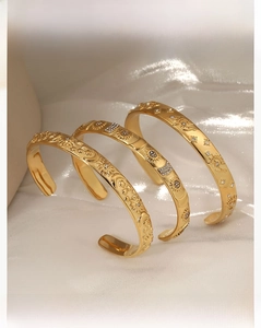 Detailed view of vintage gold bangles with embossed celestial patterns and small crystals