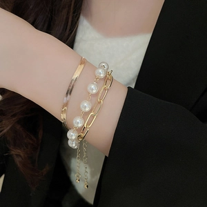 Detailed view of 3-piece layered gold-plated bracelet set with pearls on wrist