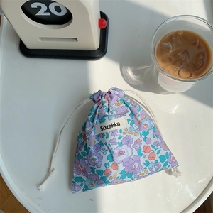 Detailed view of purple floral drawstring fabric storage bag on a white table