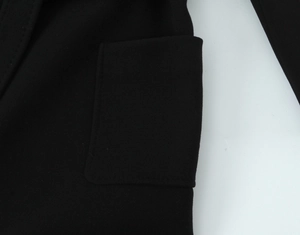 Detail of the black wool coat featuring a functional patch pocket and textured fabric