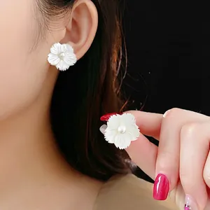 Boucles d'oreilles fleur blanche élégantes avec nacre et perle portées par mannequin