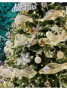 Close-up of golden and silver Christmas ball ornaments with warm lights on tree