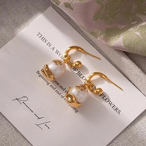 Detail of baroque pearl earrings with gold foil accents on a textured artistic background
