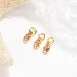 Vue macro de trois pendentifs ovales en zircon rose avec anneaux dorés pour bijoux DIY