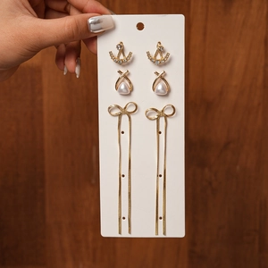 Detailed view of 3-piece gold earring set with pearls, rhinestones and bow tassels