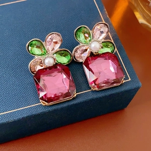 Macro shot of vintage floral stud earrings with rhinestones and square red gemstones