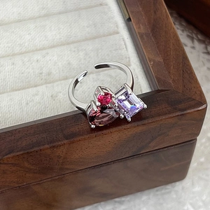 Detail of silver ring with colorful heart and pear-cut zircon on wooden box
