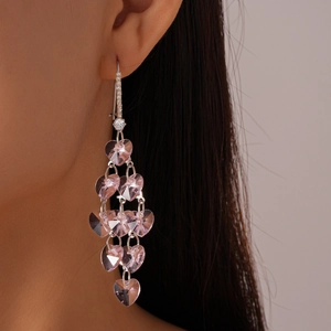 Gros plan de boucles d'oreilles cœur en cristal rose avec finition argentée sur un modèle