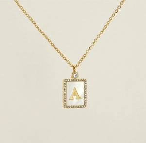 Macro detail of gold-plated rectangular pendant with white shell inlay and letter A