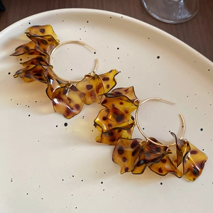 Detailed shot of gold hoop earrings with leopard print resin petals on a decorative plate