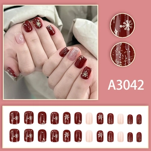 Winter red press-on nails with white snowflake patterns and silver glitter accents