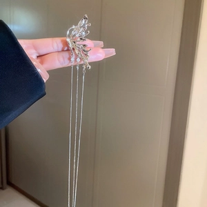 Détail d'un ear cuff papillon argenté avec de longs glands et des pierres en zircon