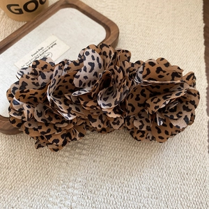 Detailed view of leopard print fabric flower hair clip with rich textile textures
