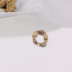 Detail view of handmade beaded ring with natural ink stone and golden beads on silk