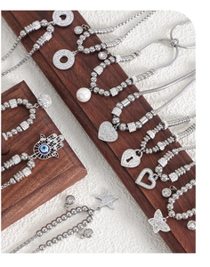 Detailed close-up of multiple silver bracelets with heart, star and hamsa hand charms