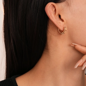 Gros plan de boucles d'oreilles créoles dorées avec opale et diamants sur un mannequin