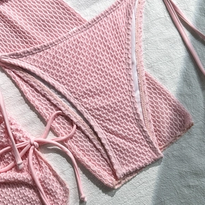 Dettaglio del tessuto a bolle rosa del bikini con trama a nido d'ape e lacci laterali