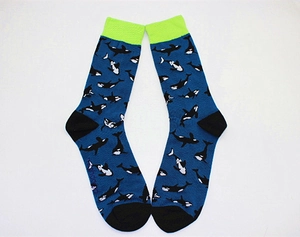 Detail of navy blue crew socks featuring orca whale patterns and neon green ribbed cuffs