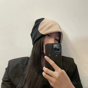 Détail du bonnet en maille double couche avec un design contrasté noir et beige minimaliste
