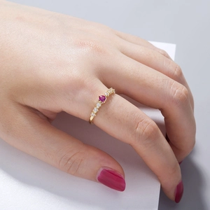 Detail of gold ring with oval red gemstone and white zircon accents on hand