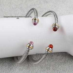 Close-up of twisted cable cuff bangle featuring pink and dark red faceted stones