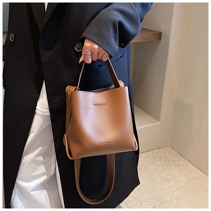 Brown leather bucket bag styled on a female model wearing a black blazer for chic daily look
