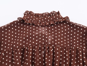 Dettaglio dello scollo a volant e del motivo a pois sulla maglia marrone da donna