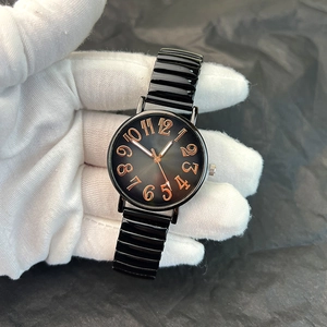 Detail of a round black dial watch with rose gold numerals and flexible spring band