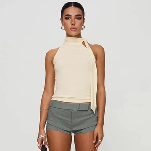 Detail eines beigen Neckholder-Tops mit Quasten und Shorts mit dekorativem Gürtel