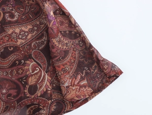 Détail du tissu en mousseline avec motifs paisley marron et coutures d'ourlet délicates