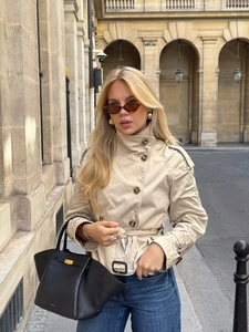 Short khaki double-breasted trench coat with belt shown in a European street style