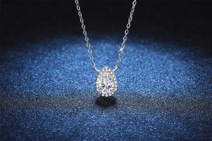 Macro shot of pear shaped Moissanite pendant with halo setting on a delicate silver chain