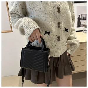 Lifestyle view of women's black quilted crossbody bag with stylish V-stitch pattern