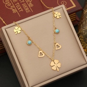 Detail of gold clover necklace with turquoise accents and hearts on a jewelry box