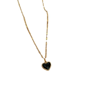 Minimalist titanium steel gold necklace with textured black heart pendant on white background