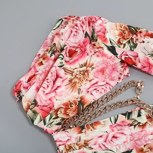 Close-up of pink floral print dress featuring gold chain straps and side zipper detail