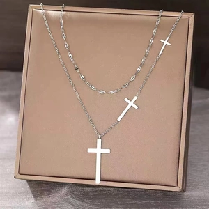 Detail of silver layered necklace with three cross pendants on a brown display board