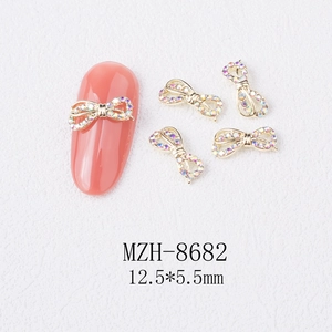 Detailed macro view of 12.5x5.5mm gold alloy bow nail charms with iridescent rhinestones