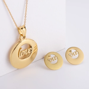 Gold plated stainless steel jewelry set with hollow love pendants on white pedestal