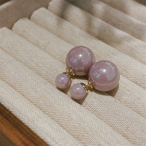 Detail of elegant dusty pink double pearl earrings on a beige velvet jewelry tray